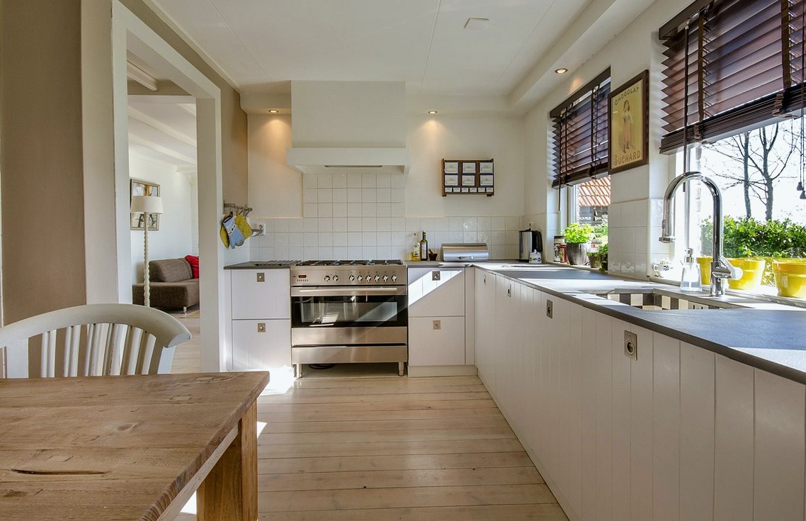 White kitchen with tiled splashback, dark worktops, a range cooker and timber floor