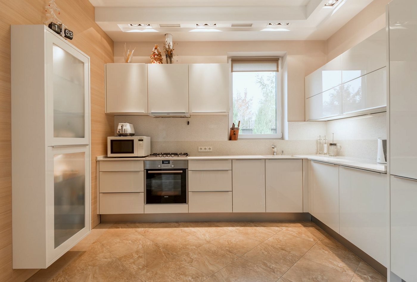 Cream fitted kitchen with white worktops and tiled flooring