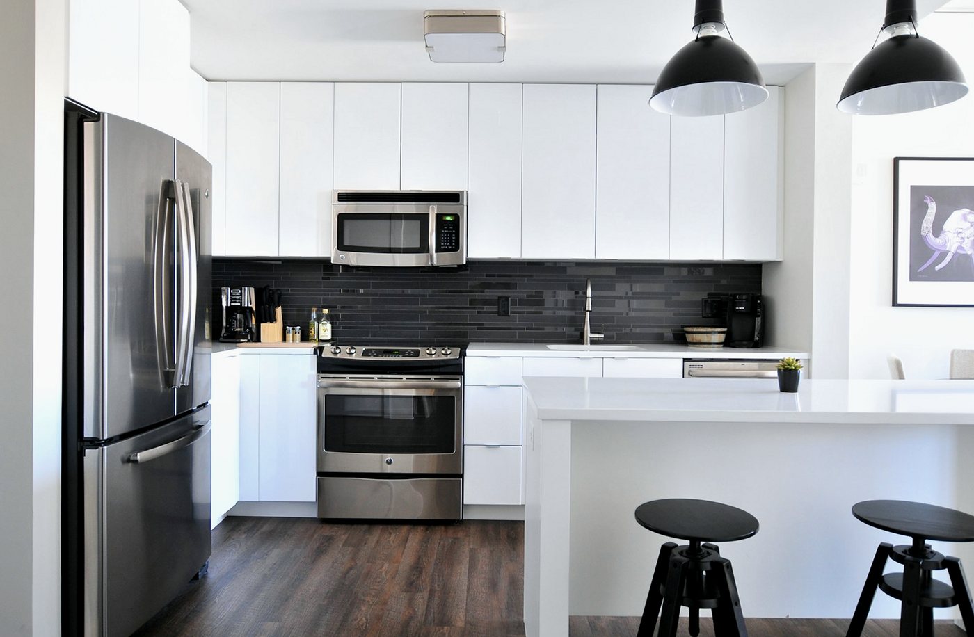 White kitchen makeover with a dark subway-tiled splashback and a white worktop island
