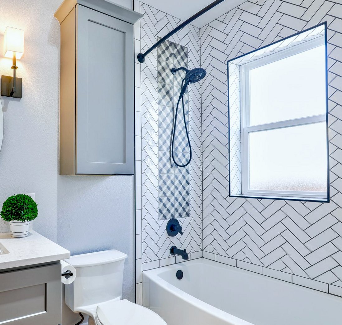 White herringbone wall tiles fitted around a shower and bath