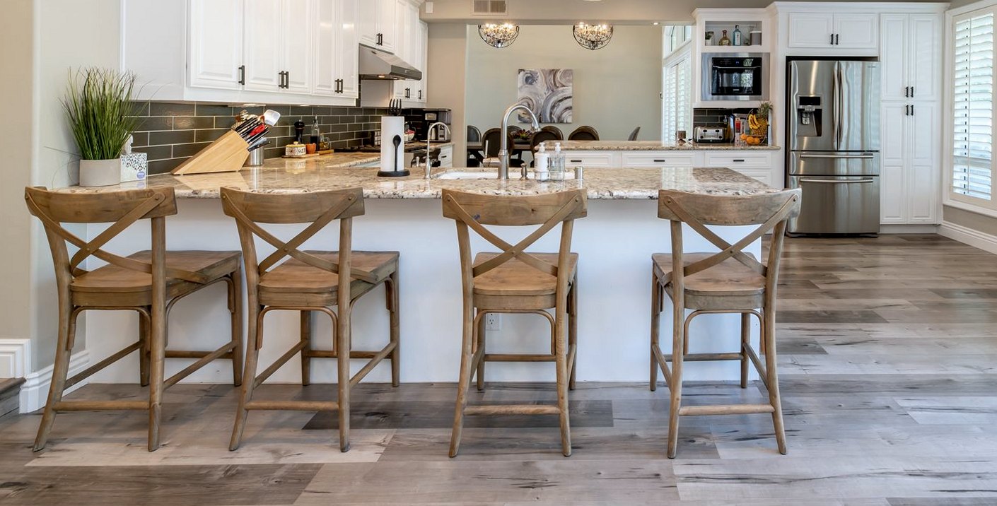 Granite kitchen worktop on a fitted island with an undermount sink and bar stools